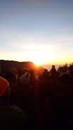 Sunrise over a peaceful gathering of people holding hands in nature.