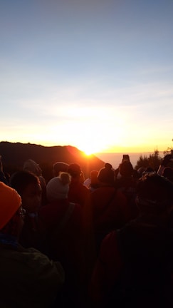 A group gathered in a warm circle during a sunrise devotional outside.