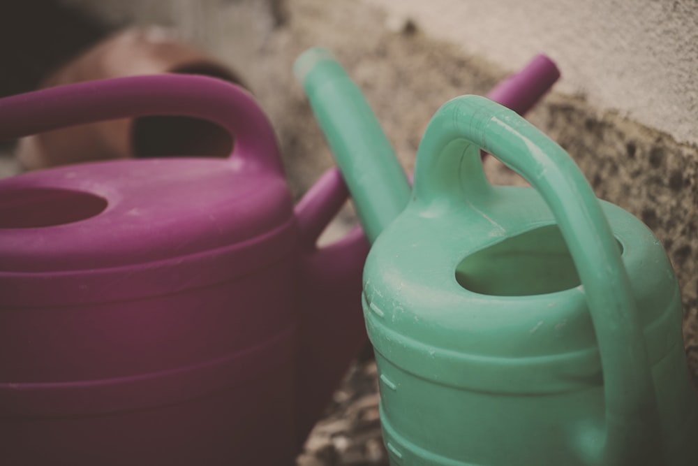 two green and pink watering cans