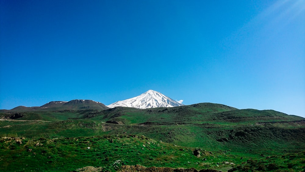 uma neve - montanha coberta eleva-se acima de um vale verde