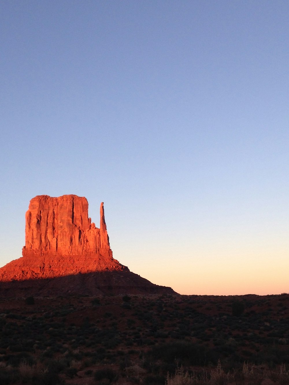 Un'alta formazione rocciosa rossa nel mezzo di un deserto