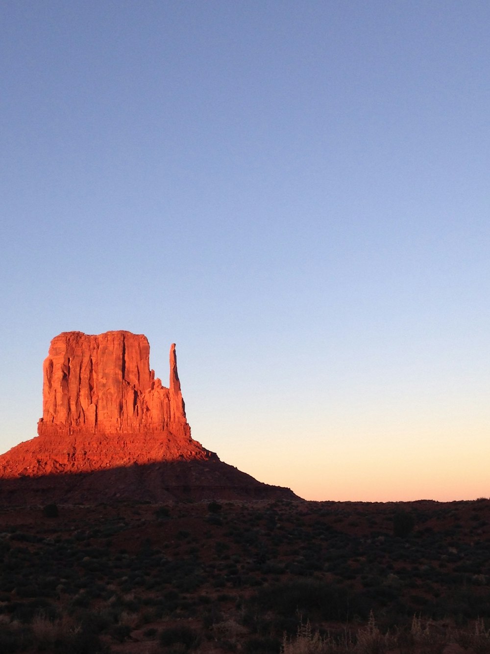 a tall red rock formation in the middle of a desert