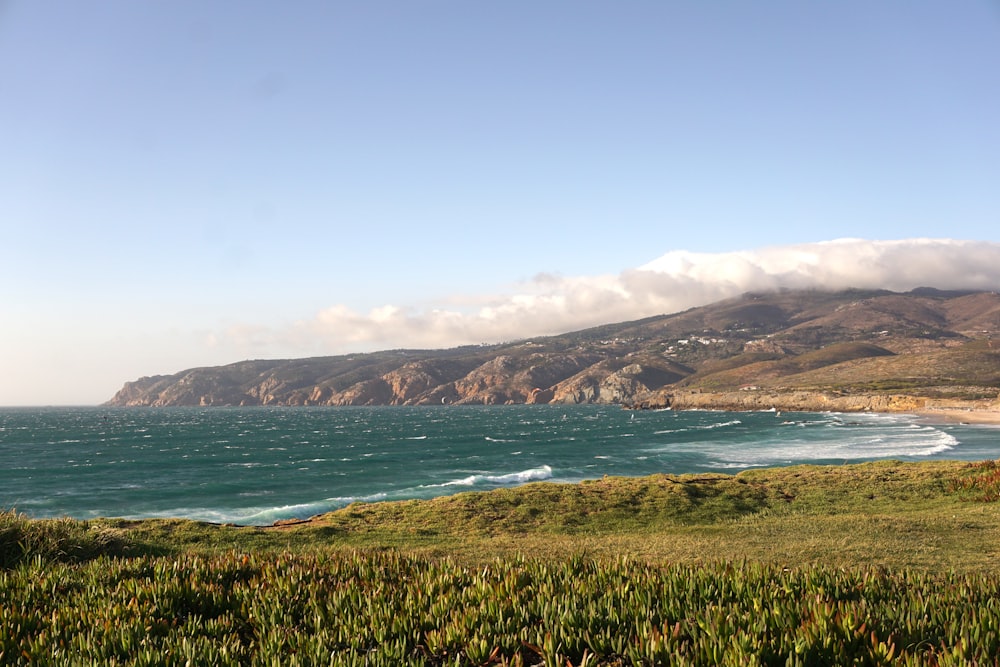 a scenic view of the ocean with a mountain in the background