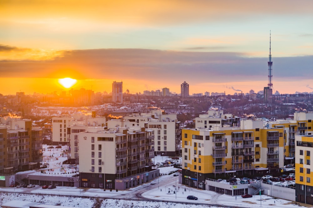 the sun is setting over a city with tall buildings