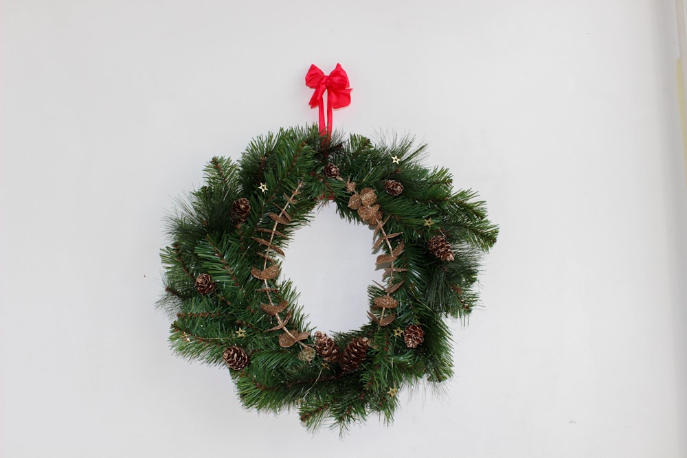 a christmas wreath with a red bow hanging on a wall
