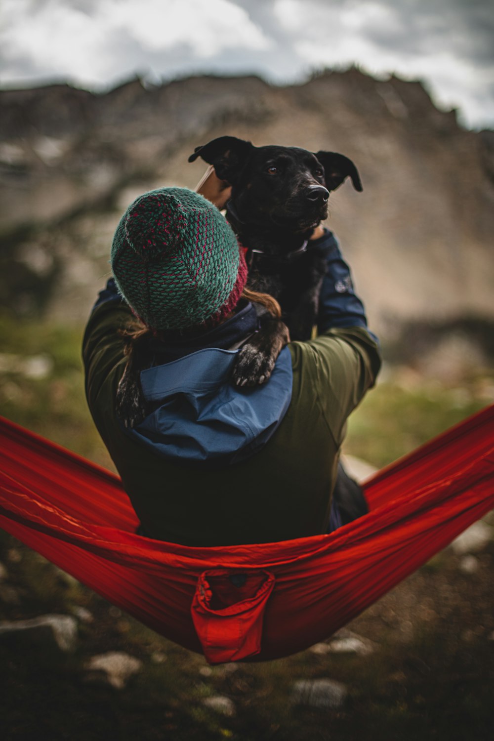 a person sitting in a hammock with a dog