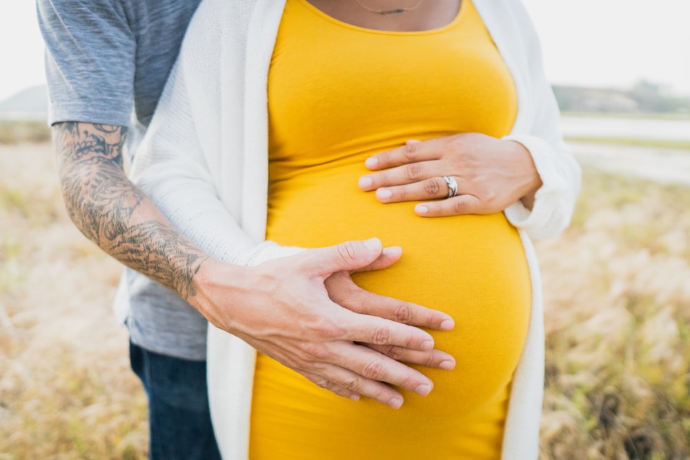 man hugging pregnant woman on her back during day