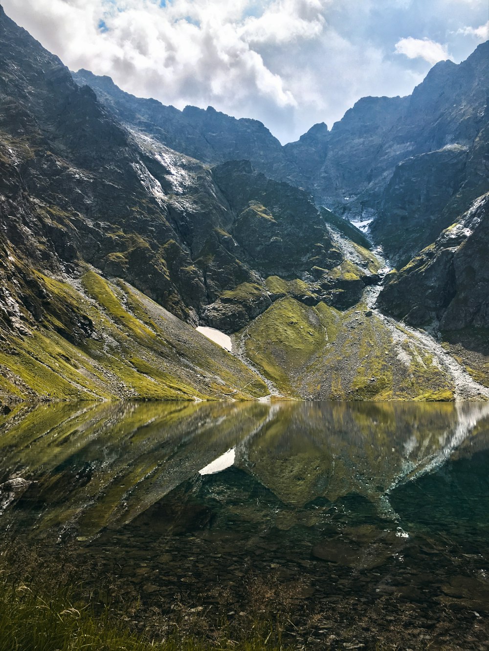 reflection of green mountains on body of water during daytime