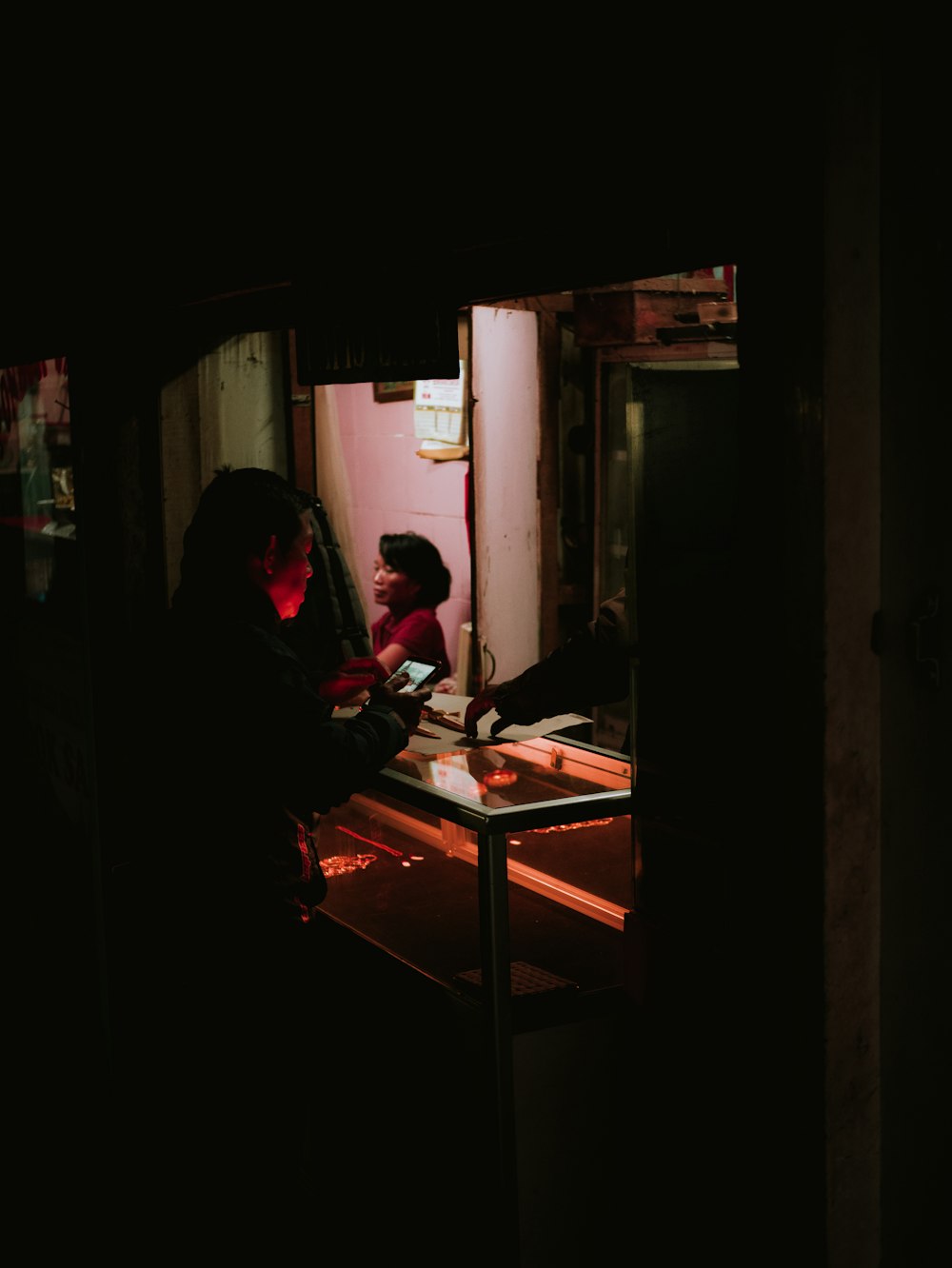 man leaning over a glass counter