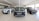 A showroom with several Land Rover vehicles displayed prominently on a glossy tiled floor. The vehicles include a white SUV, a black Discovery Sport, and a silver SUV. Bright natural light streams in through large windows, illuminating the area.