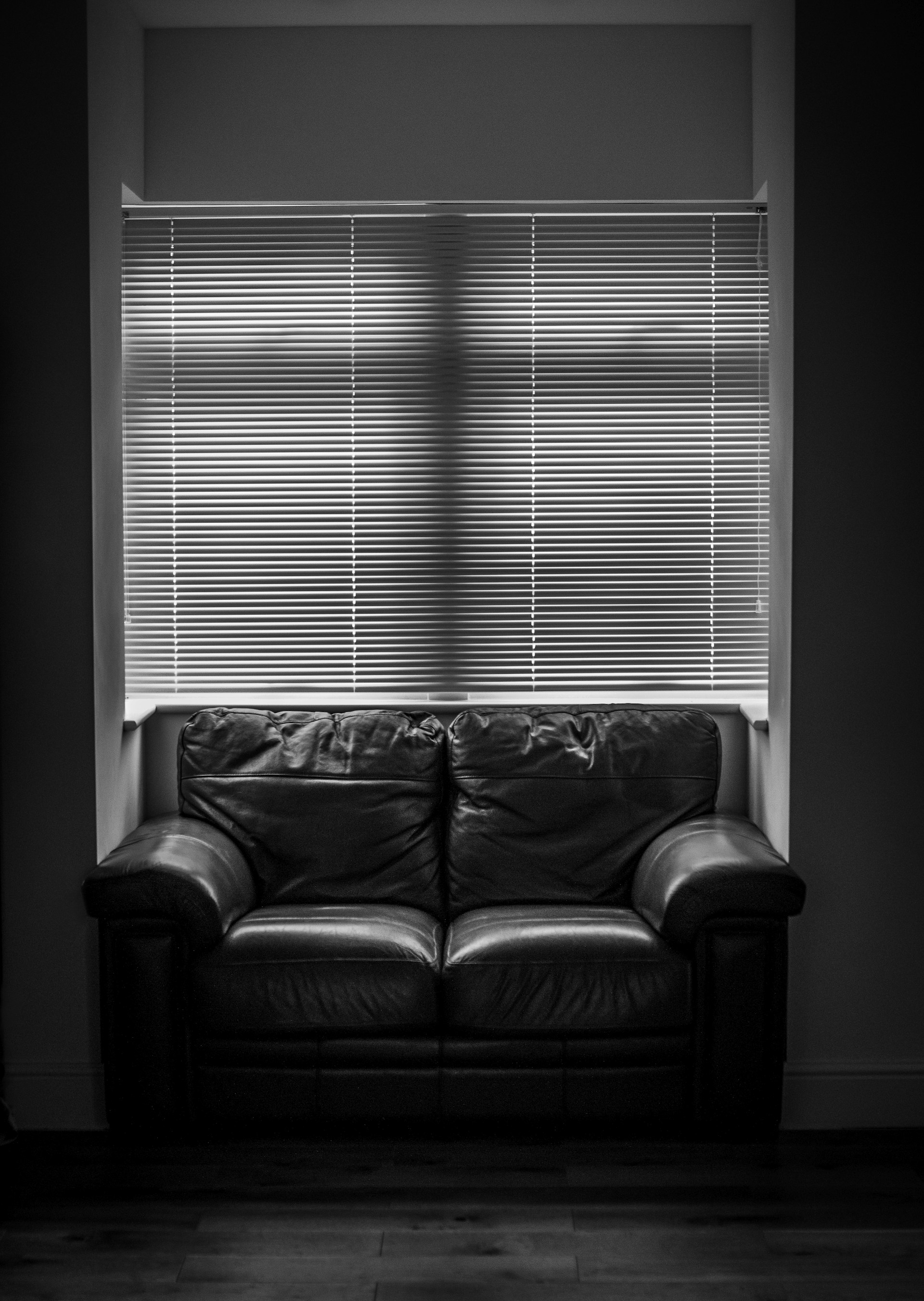 a black and white photo of a couch in front of a window