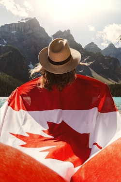 woman carrying flag of Canada near mountains