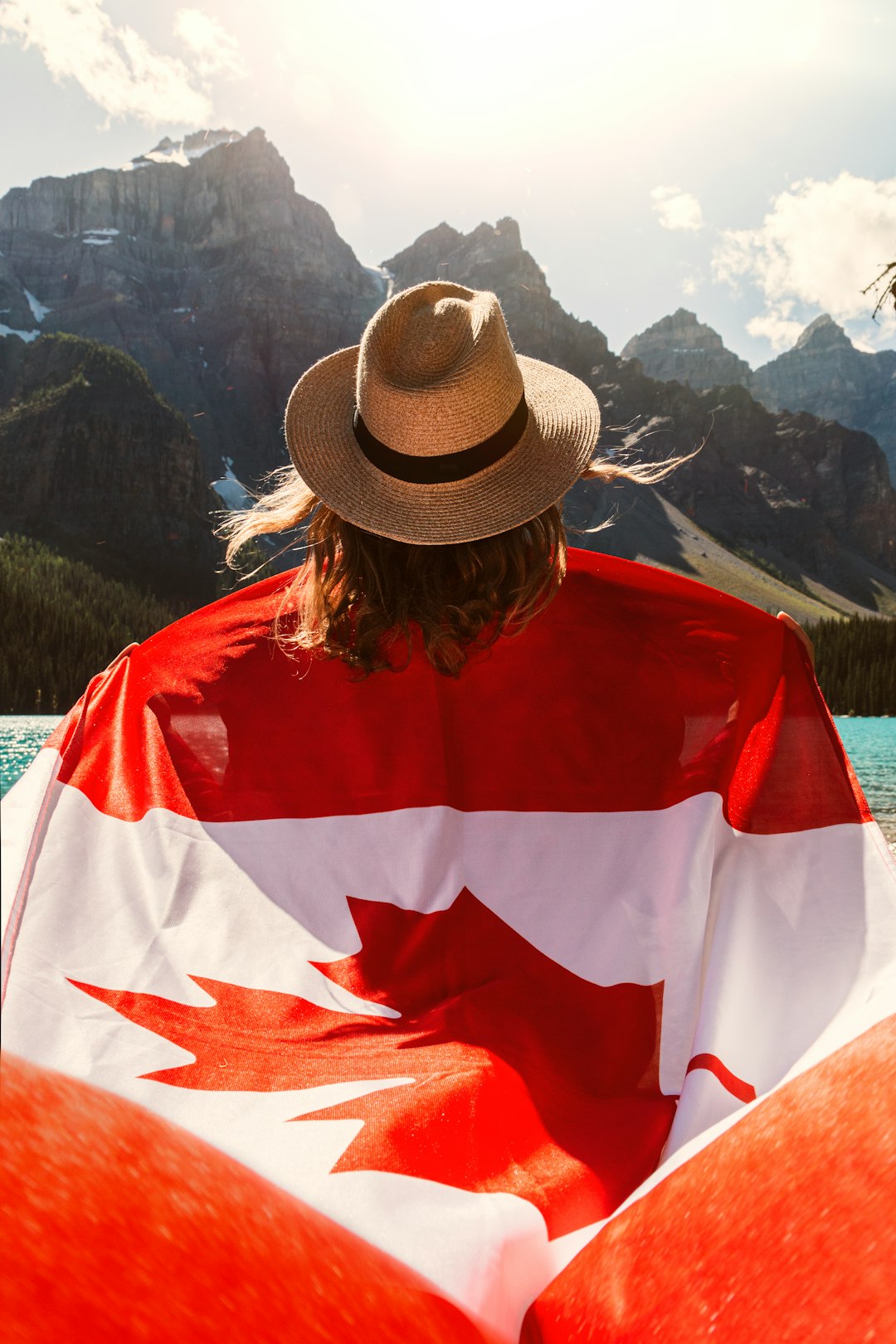 woman carrying flag of Canada near mountains