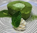 A vibrant green matcha dessert with delicate white chocolate shavings on top.