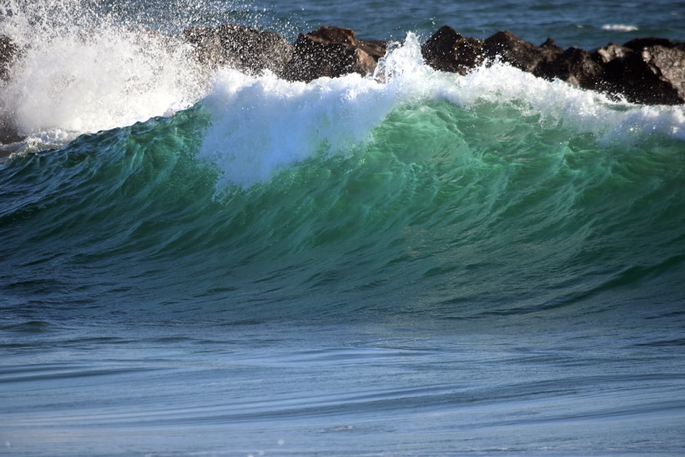 green sea wave near rock formations during daytime