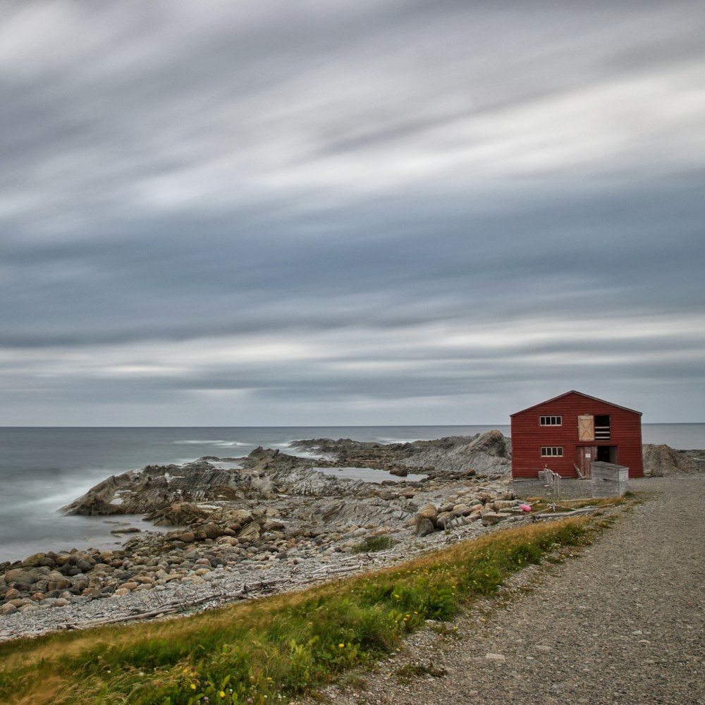 Casa de madera roja cerca de la orilla del mar durante el día