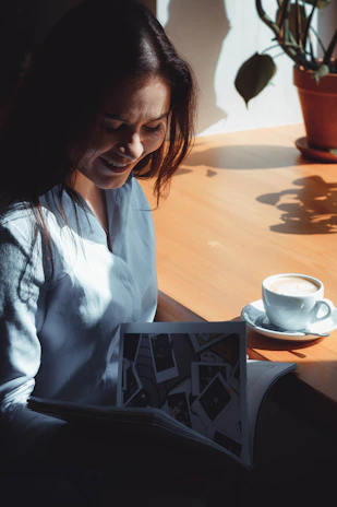 A cheerful woman reading a blog article on her tablet in a bright, airy room filled with plants.