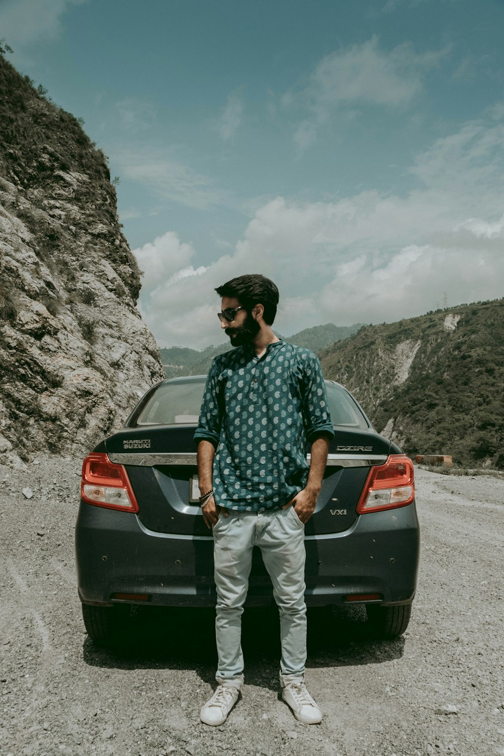 man standing beside gray car