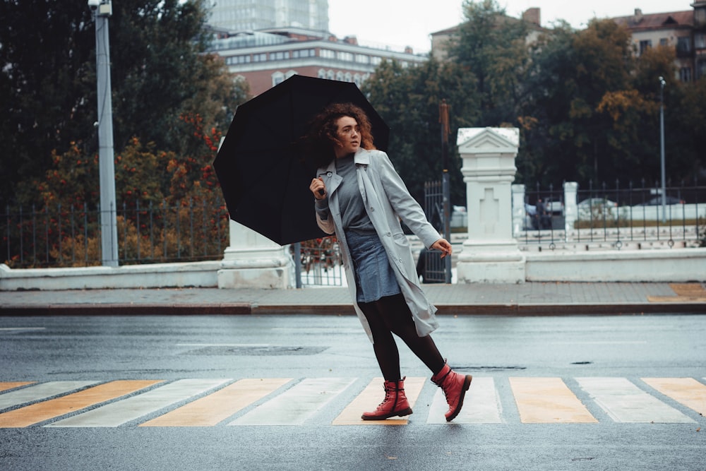 woman crossing pedestrian lane and holding umbrella