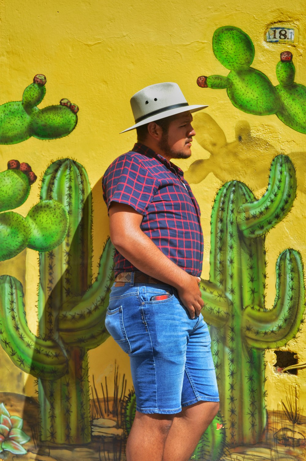 man standing beside wall with cacti mural