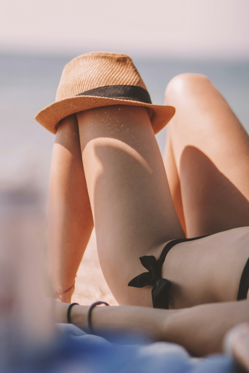 a woman laying on top of a beach next to the ocean