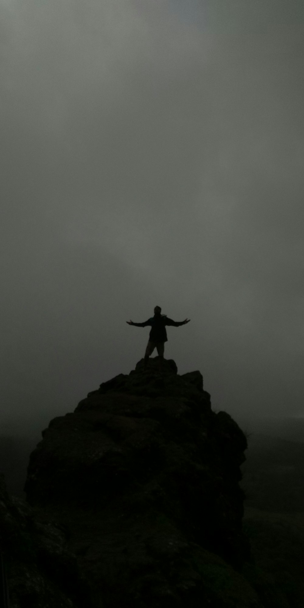 silhouette of person standing on cliff