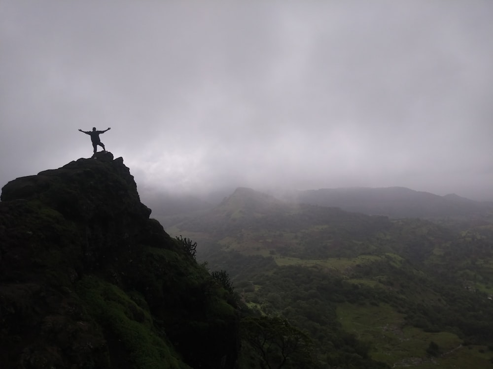 silhouette of person standing on cliff