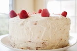 round white icing covered cake with raspberries