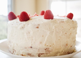 round white icing covered cake with raspberries