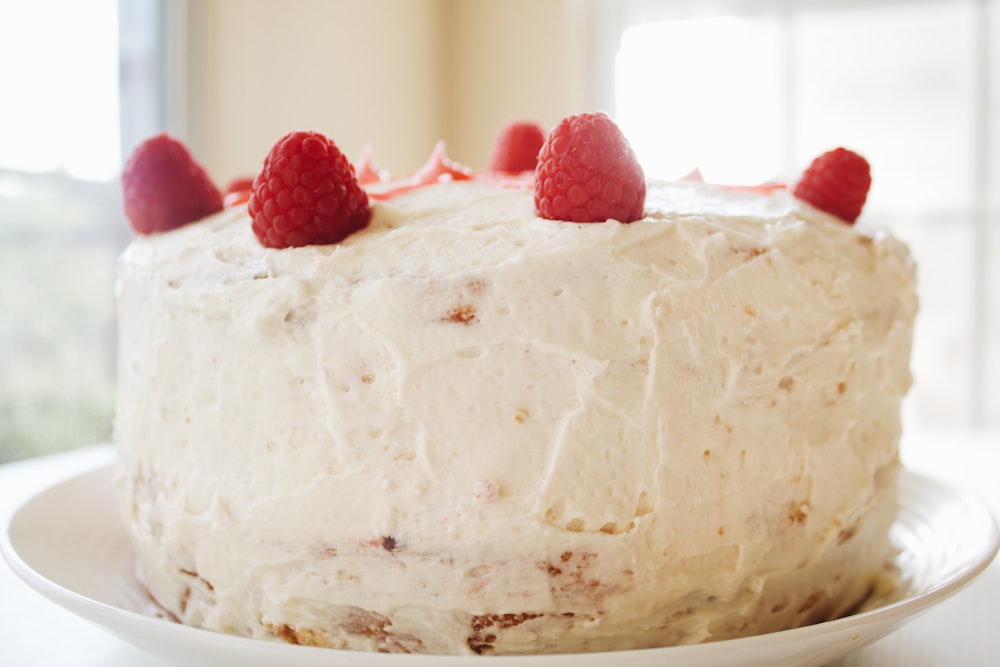 round white icing covered cake with raspberries