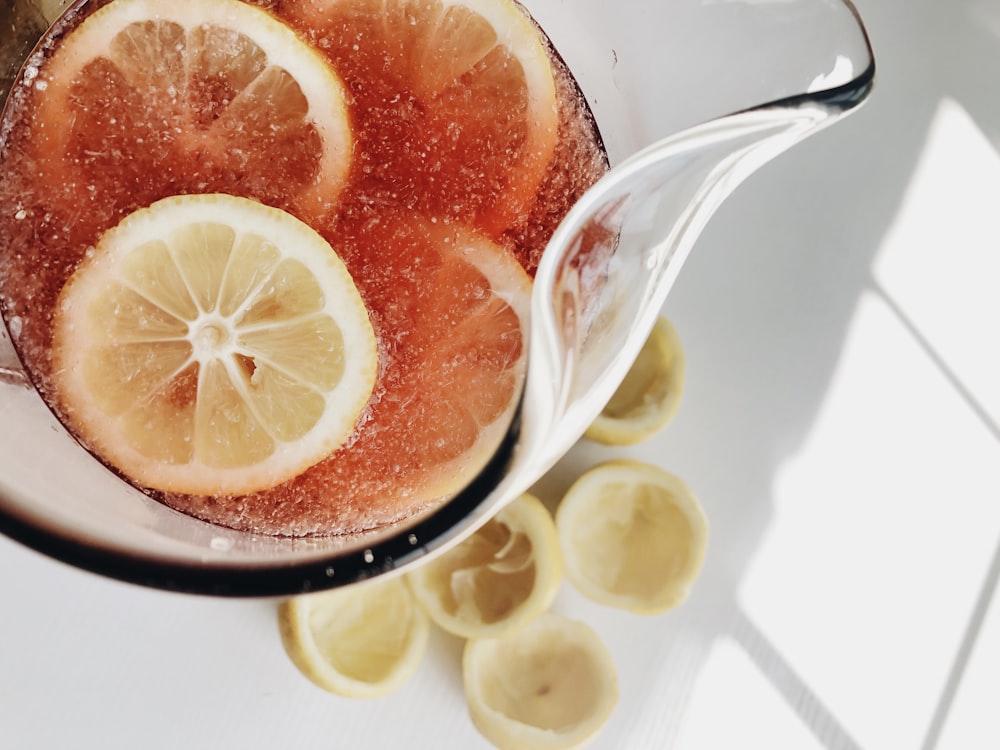 a pitcher filled with liquid next to sliced lemons
