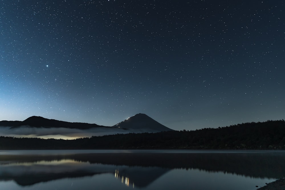a lake with a mountain in the background at night