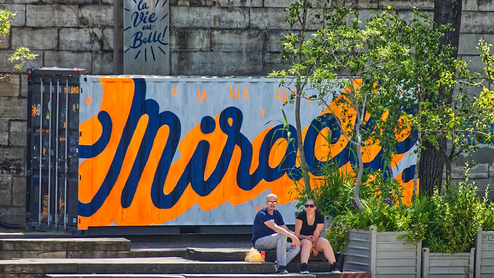 two person sitting on bench beside tree at daytime