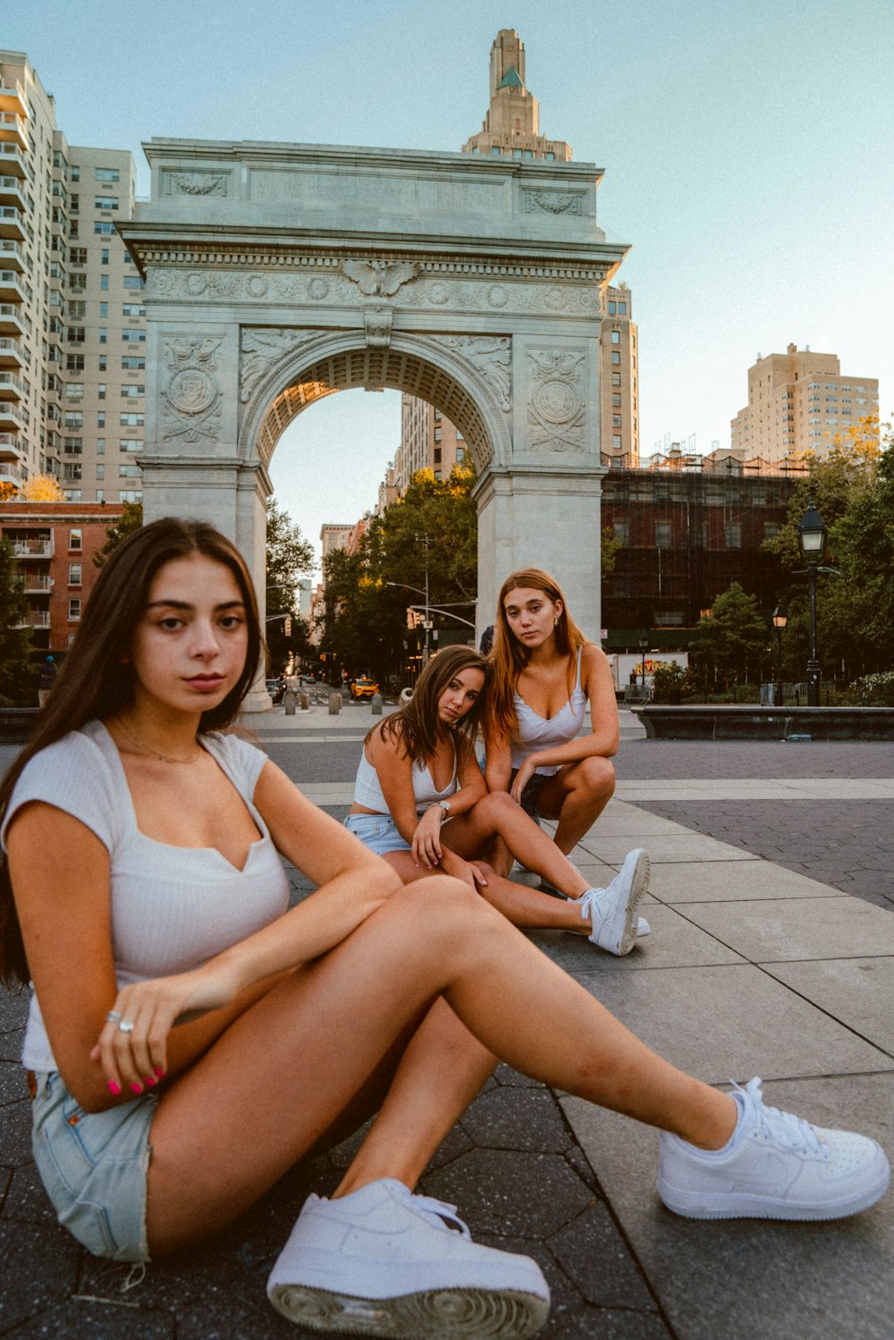 three women sitting near arch during daytime