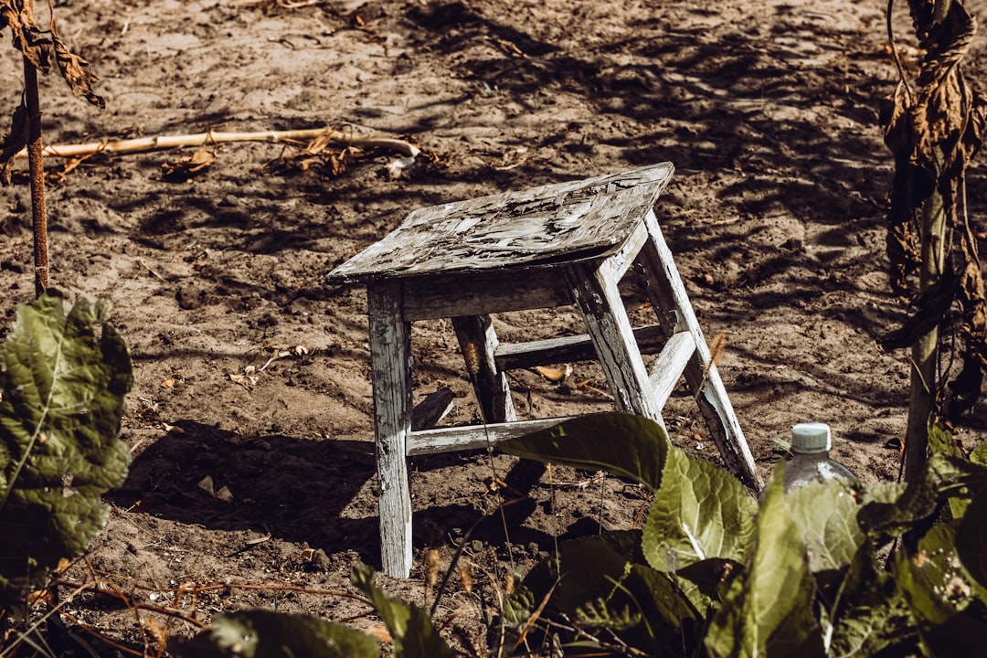 dirt covered white wooden stool on soil ground