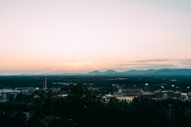Sunset view over the Broncos stadium with the city skyline in the background.