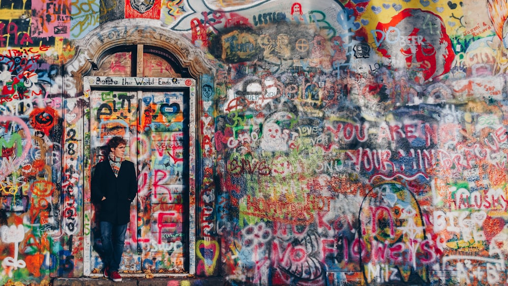 man standing front of graffiti wall