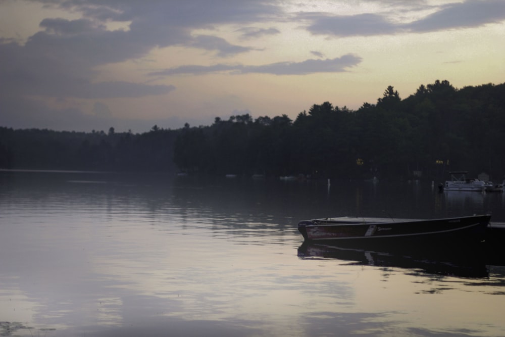 empty red boat on calm body of water near trees