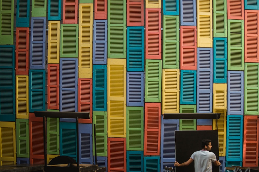 man standing front of m,multicolored wall