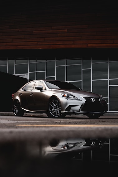 A sleek luxury sedan parked in front of a modern office building at sunset.