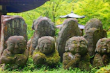 Ancient stone statues partially covered in moss, nestled in a quiet garden.