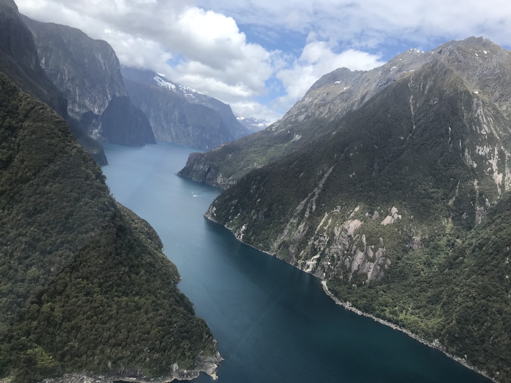 body of water between mountains under cloudy sky during daytime