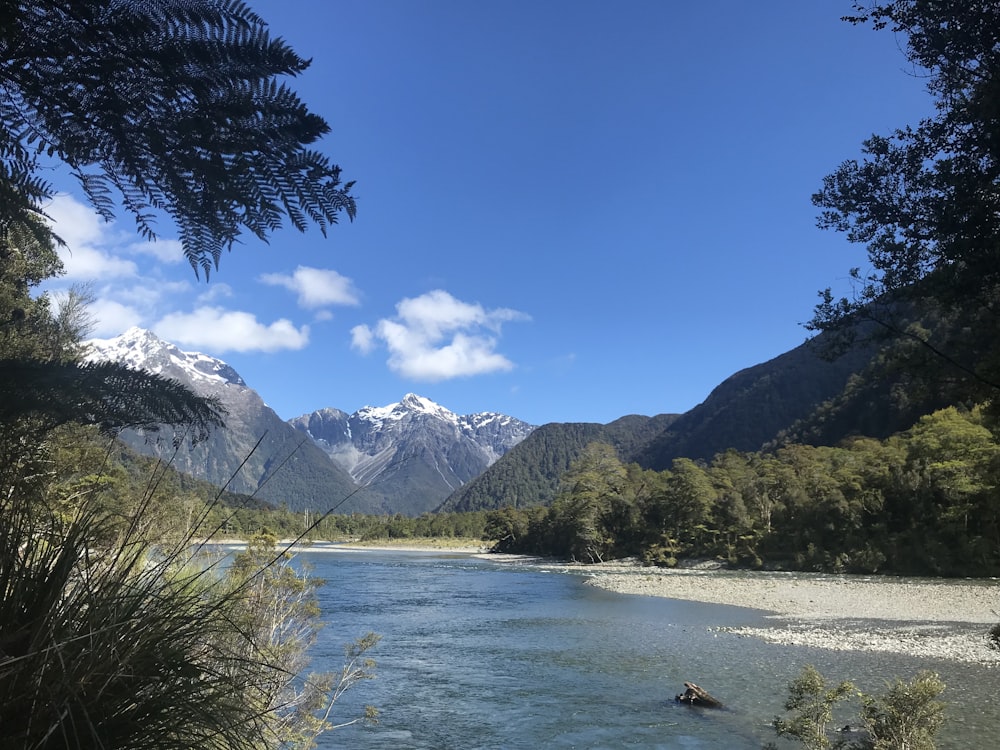 body of water fcifacing mountains under blue sky