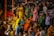 A group of people gathered in colorful traditional attire, engaged in a ritual or prayer at a public event or ceremony. The crowd is diverse, with a mix of men and women, some sitting while others stand with folded hands. The atmosphere suggests a cultural or religious significance.