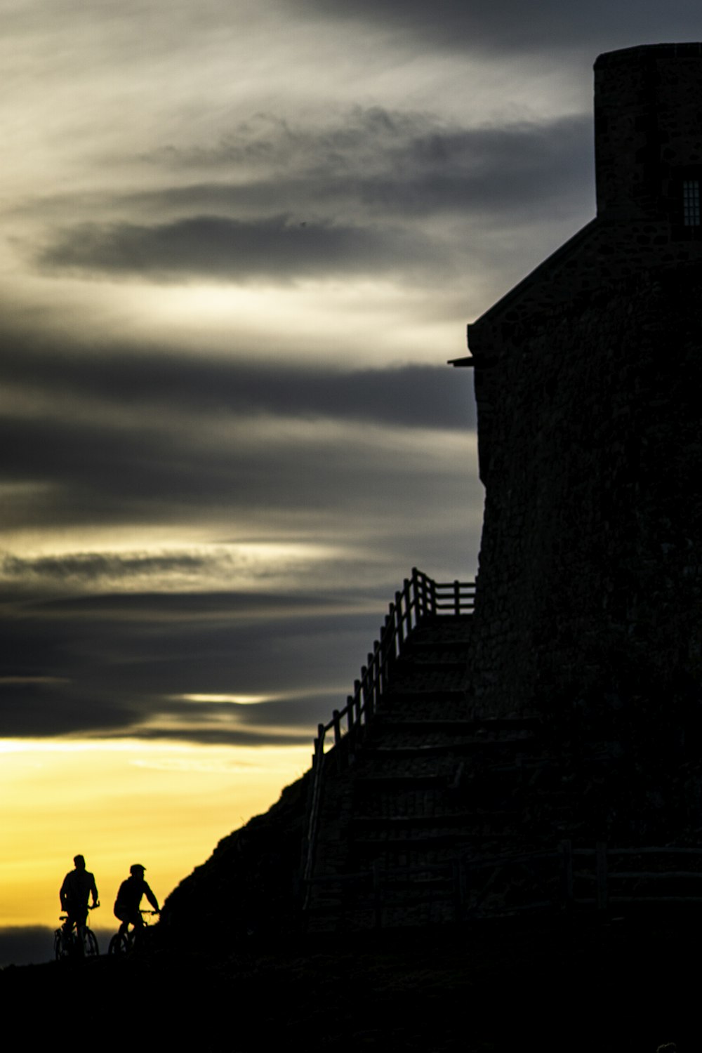 silhouette of 2 person riding bicycle besides hills with stair