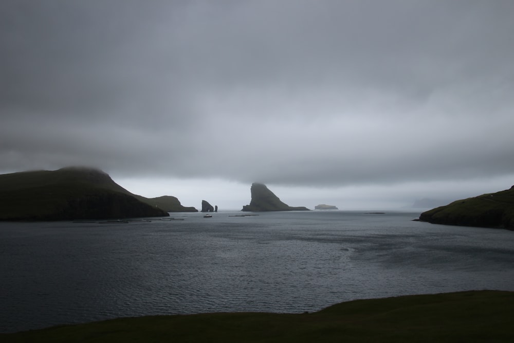 a body of water surrounded by mountains under a cloudy sky