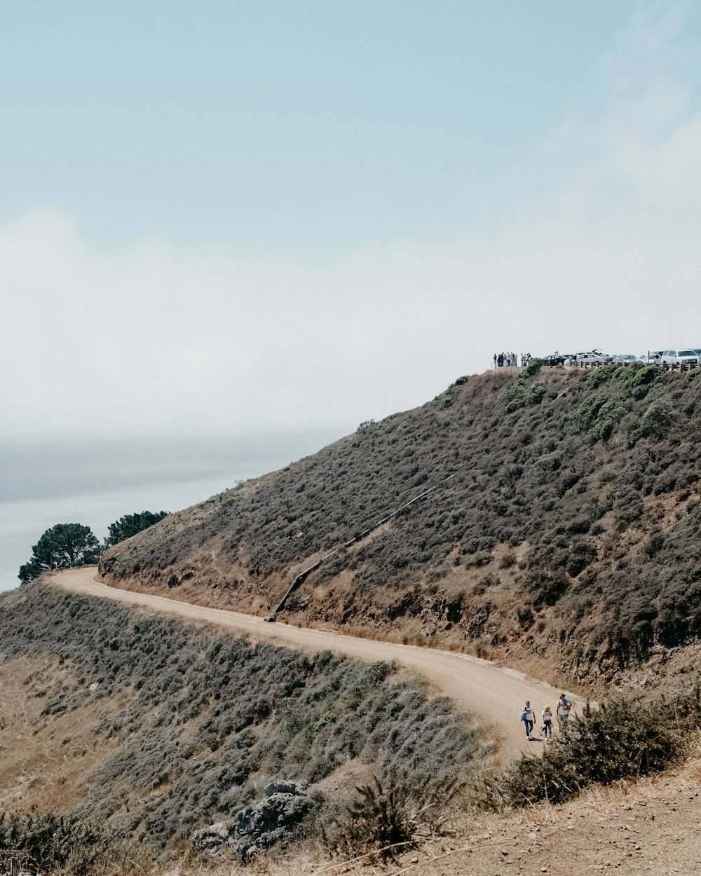 three persons walking on mountain dirt road