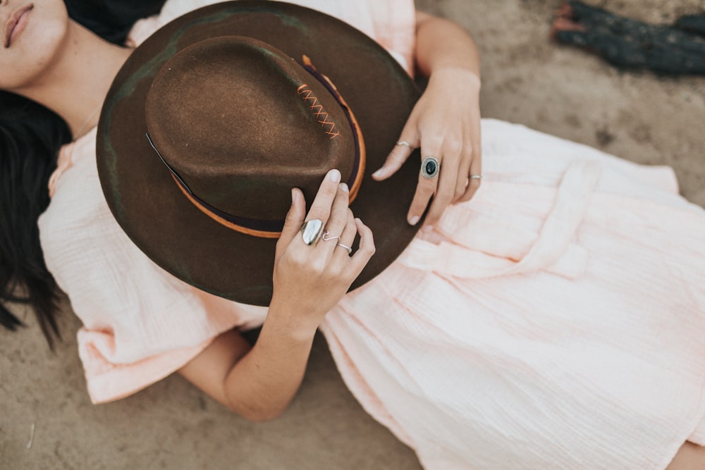 woman wearing pink dress holding brown cowboy hat