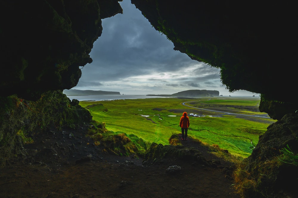 person standing at edge of mountain under cloudy sky