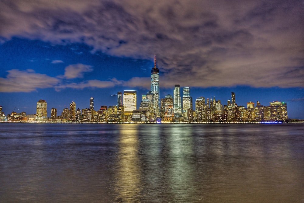 calm water front of lighted buildings at night time